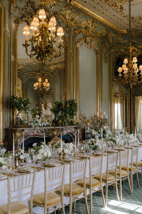 an elaborately decorated dining room with chandeliers and white table cloths, gold trimming