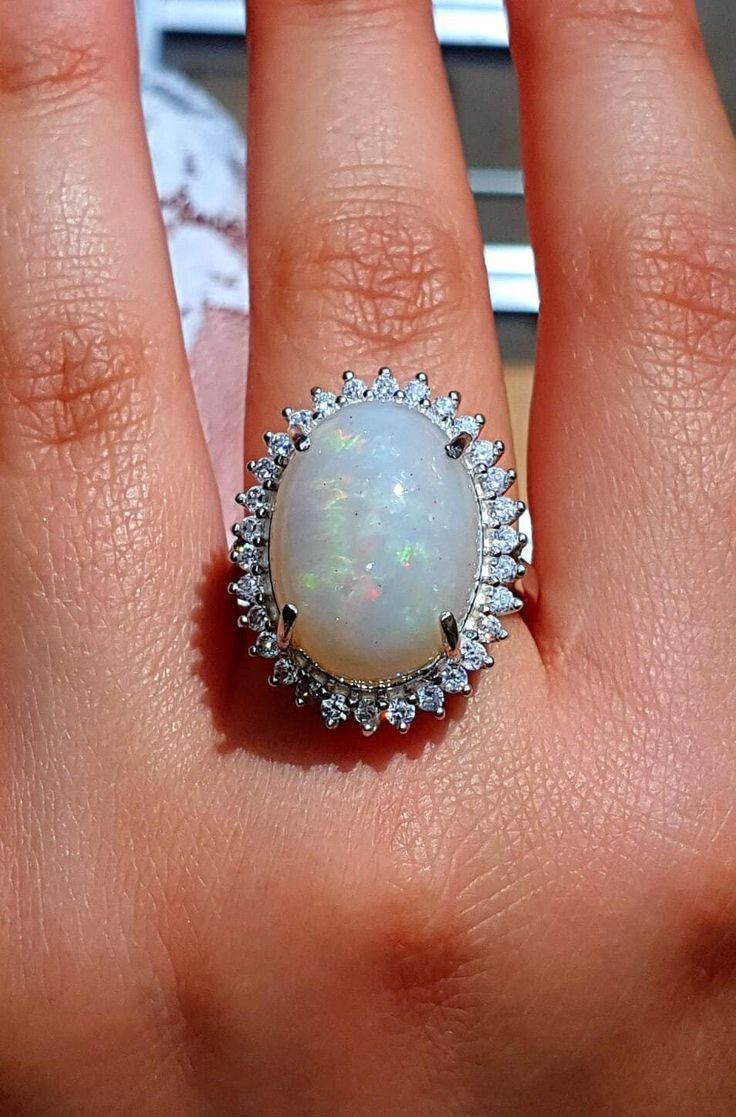 "★★Opal is one of the most favored gemstones among women. It is about the play of color in that natural Opal gemstone, that attracts the eyes,  you simply cannot take your eye off it. My love for unique gemstones brings me to look for unusual, one-of-a-kind gemstones, like the one set in this ring. ★★This 14k solid gold ring is set with a -  genuine - natural - huge - Ravishing - One of kind-rainbow fire Opal. The kind of Opal that your eyes just can't get enough of. ★★This fire Opal weighs 10.3 carats in size 19x14 mm (0.75 inches). It is a large Ethiopian Opal ring, the Opal looks stunning in the sunlight. The colors it reveals in the sunlight are amazing blue, green, red, and gold. ★★The Opal is surrounded by 1.8 carats of natural high-grade nature 2 mm brilliant white diamonds in a hal Big Opal Ring, Exquisite Multi-stone Oval Opal Ring, Exquisite Oval Multi-stone Opal Ring, Fine Jewelry White Diamond Gemstones, Exquisite Oval Opal Ring, White Multi-stone Moonstone Ring For Formal Occasions, Fine Jewelry Opal Ring With Halo, White Oval Cluster Ring Hallmarked, Oval White Cluster Ring Hallmarked