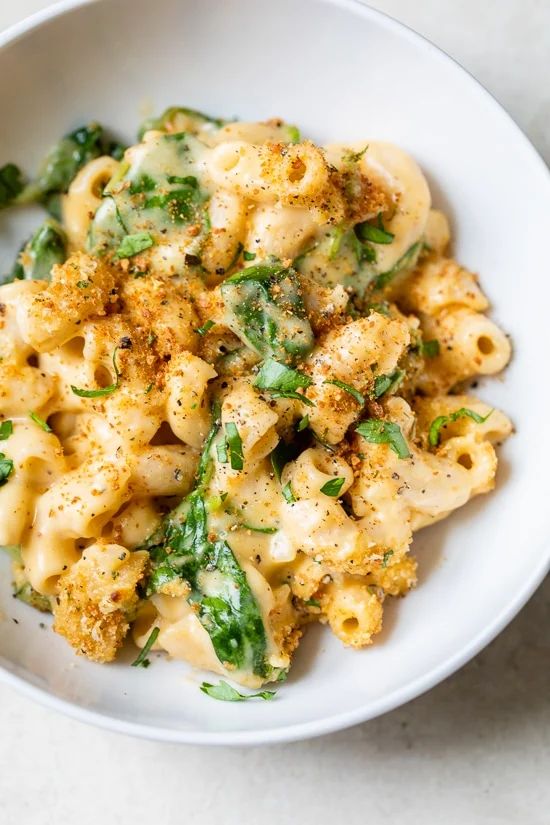 a white bowl filled with macaroni and cheese covered in broccoli florets