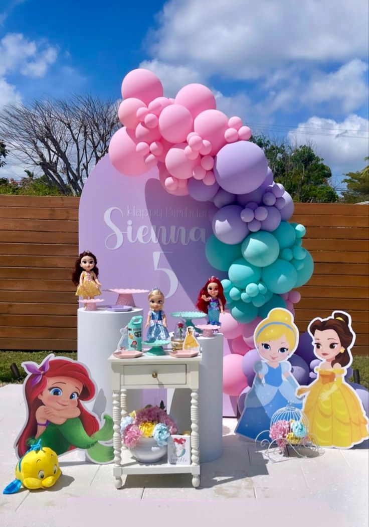 an outdoor birthday party with balloons and princess figurines