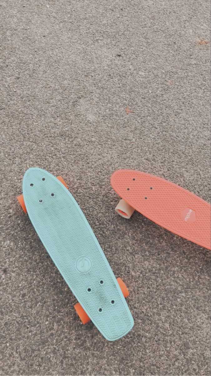 two skateboards laying on the ground next to each other, one is blue and orange