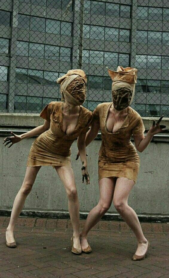 two women dressed in costumes standing next to each other on a brick floor near a building