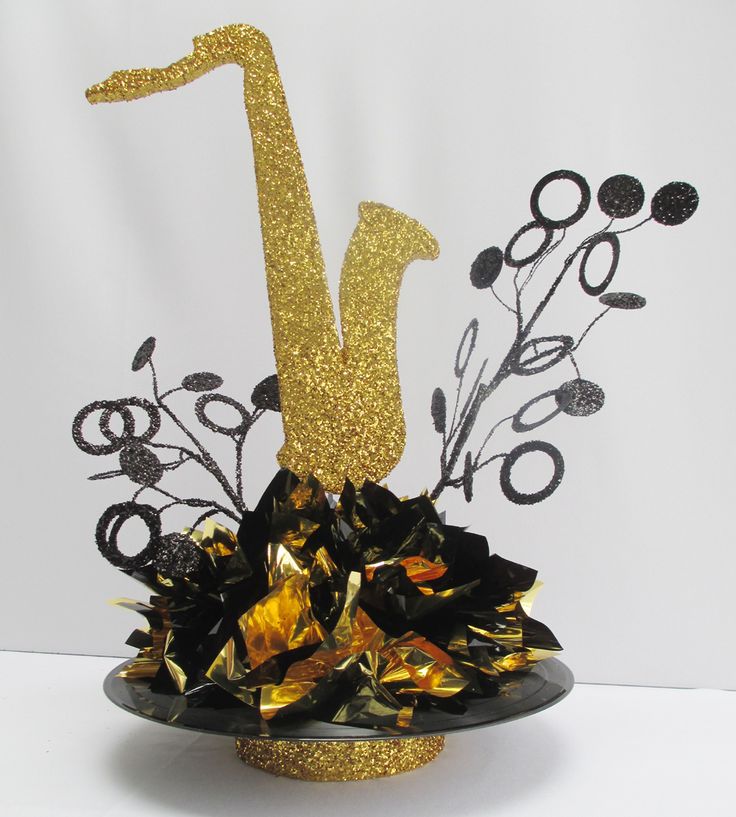 a gold and black cake topper with a saxophone on it's head, surrounded by flowers