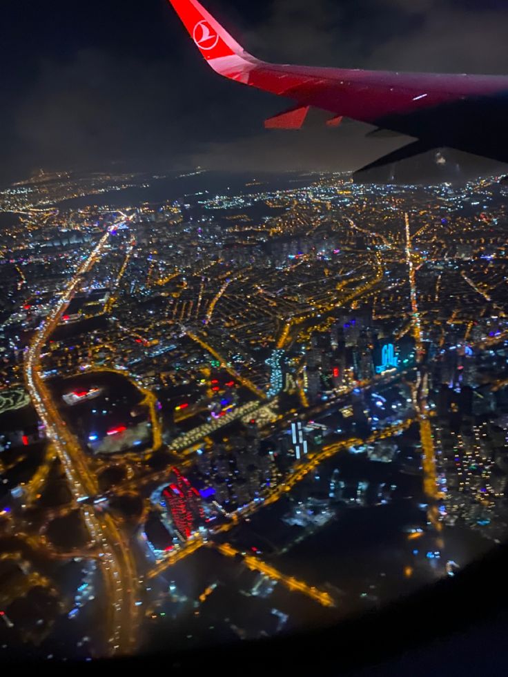 an airplane wing flying over a city at night