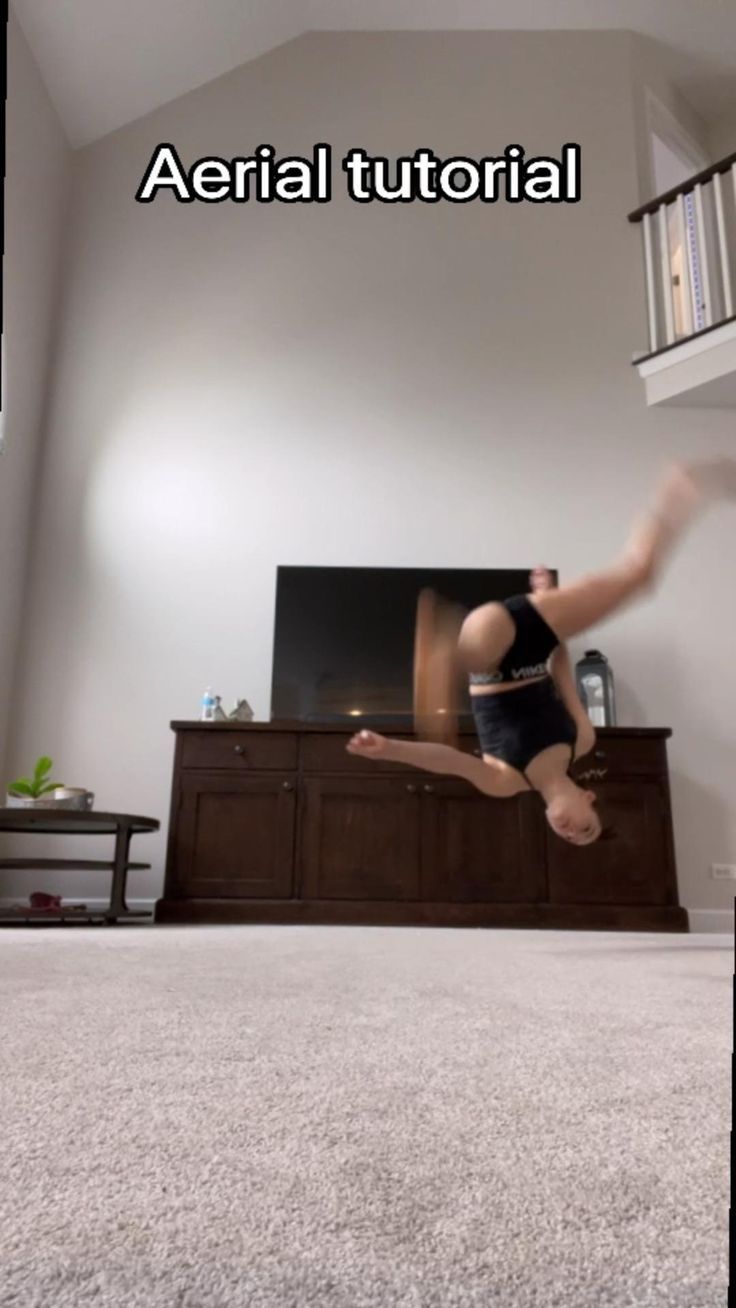 a person doing a handstand on the floor in front of a flat screen tv