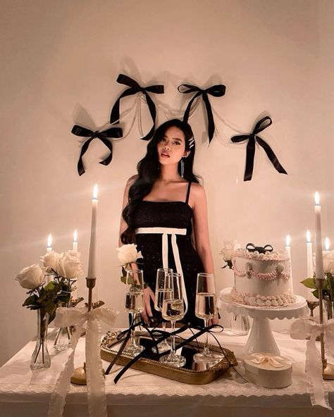 a woman standing in front of a table with cake and wine glasses on top of it