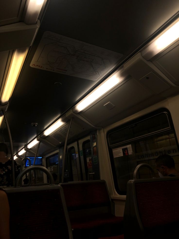 the interior of a subway car at night with lights on and people sitting in seats