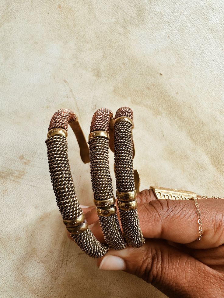 A beautifully handcrafted torque style brass cuff, accented with twisted brass, copper and lightly textured brass beads. Each bracelet is adjustable and can be adjusted to fix smaller or larger wrist. Handmade by African artisans in Kenya. DETAILS: Unisex Metal: Solid Brass & Copper Ships with polishing cloth for everlasting wear. Due to the handmade nature, expect slight imperfections. Each is one of a kind. *Packaged for gift giving. *Sold Individually (1 Bracelet). Not a set. Antique Gold Adjustable Metal Bracelets, Adjustable Wire Wrapped Bronze Cuff Bracelet, Adjustable Copper Braided Bohemian Bracelet, Adjustable Copper Bohemian Braided Bracelet, Adjustable Bohemian Copper Braided Bracelet, Adjustable Artisan Metal Bangle, Adjustable Antique Gold Metal Cuff Bracelet, Adjustable Bronze Copper Bangle, Adjustable Brass Beaded Bracelets