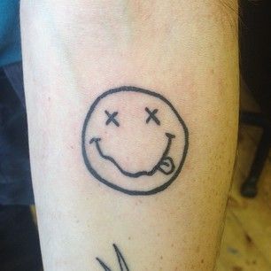 a person with a smiley face tattoo on their left arm and the word smile written in black ink