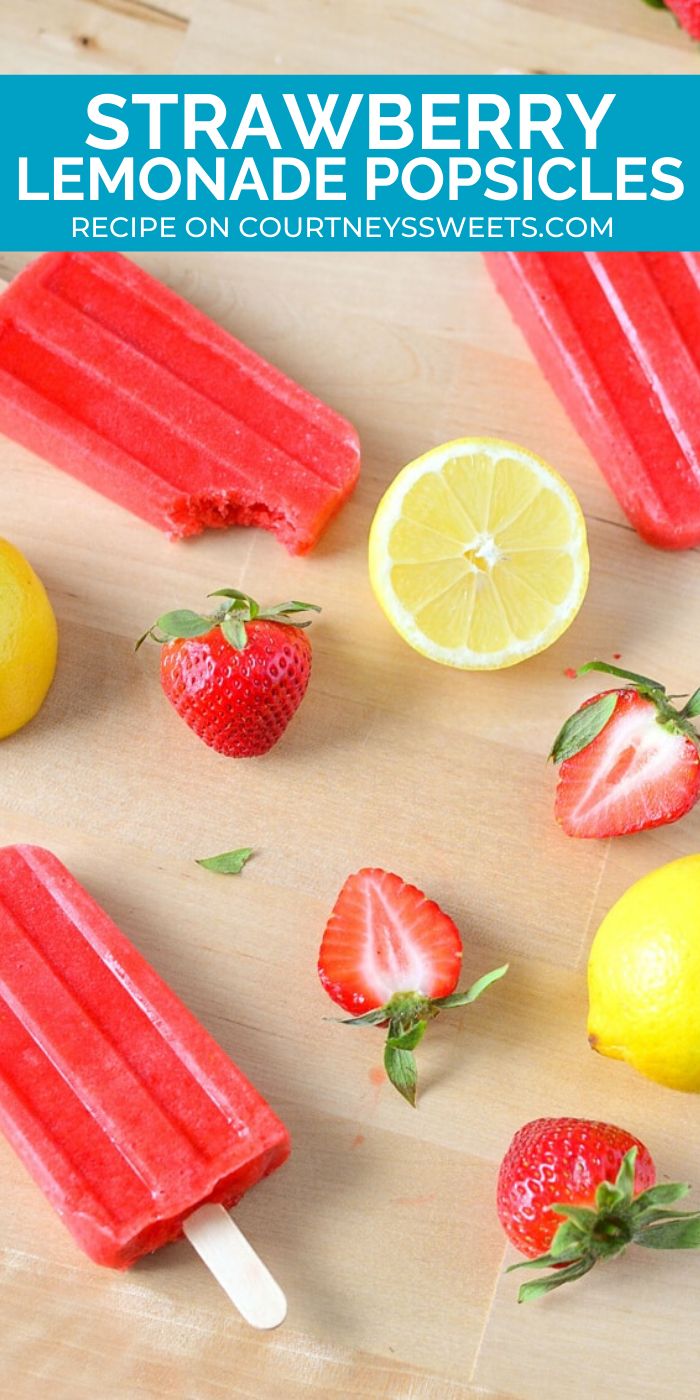 strawberry lemonade popsicles on a cutting board with strawberries and lemons