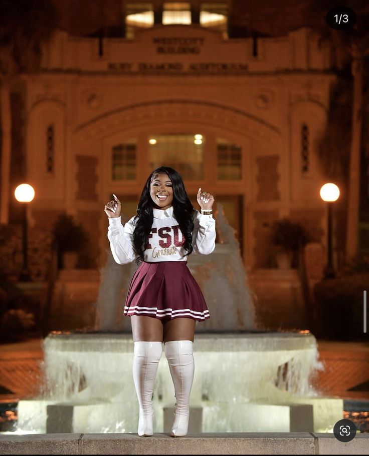 a woman in a cheerleader outfit is posing for the camera with her hands up