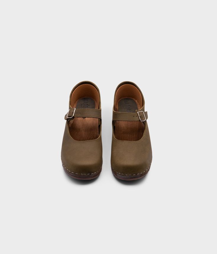 Mary Jane – the perfect blend of style and comfort. Handmade in Sweden, these low-heeled closed-back clogs are a must-have for any conscious customer looking to add sophistication to their wardrobe. With an undeniable cute factor, you'll feel confident and on-trend with every step. Clog measurements:Heel height: 1 3/4” (4.45 cm)Toe height: 1 5/8″ (4.1 cm)Fit:RegularLeather:Nubuck leatherClogs consist of:Base: European lime woodSole: Rubber soleFastening: StaplesOther: Metallic Buckle Casual Brown Non-slip Clogs, Brown Suede-lined Clogs With Round Toe, Brown Slip-on Clogs With Rubber Sole, Brown Leather Clogs With 4-inch Heel, Mary Jane Clogs, Brown Clogs With Buckle Closure, Medium Width, Cork Sandals, Clog Sandals, Wooden Clogs