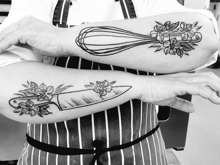 black and white photo of two people with tattoos on their arms, one holding a whisk