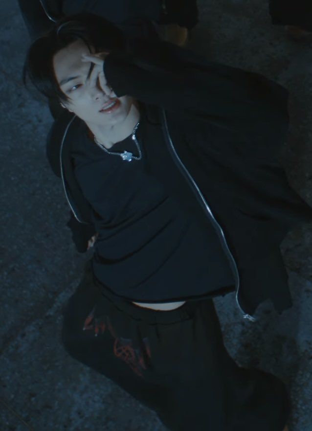 a woman laying on the ground with her head in her hands and wearing black clothing