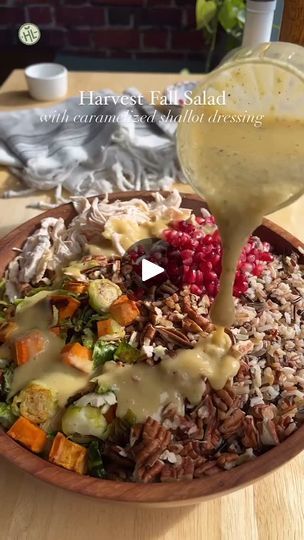 a wooden bowl filled with rice and veggies covered in gravy being drizzled over it