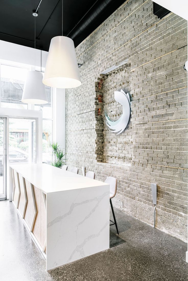 an office with brick walls and white marble counter tops, along with modern lighting fixtures