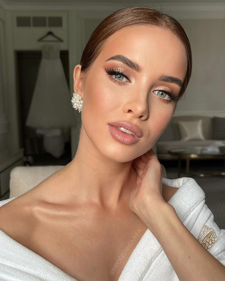 a woman in a white dress posing for the camera with her hand on her chin