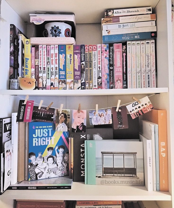 a book shelf filled with lots of books next to a microwave and other items on top of it