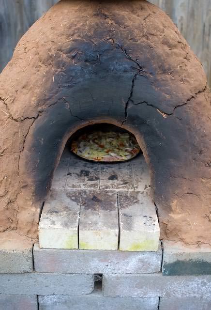 a pizza is cooking in an outdoor oven with no one around it or on the outside