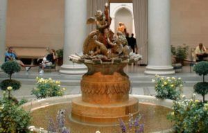 a fountain in the middle of a building with people sitting around it