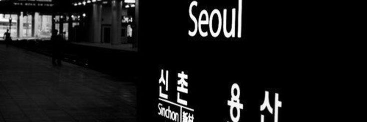 a black and white photo of people walking down the street at night with lights on