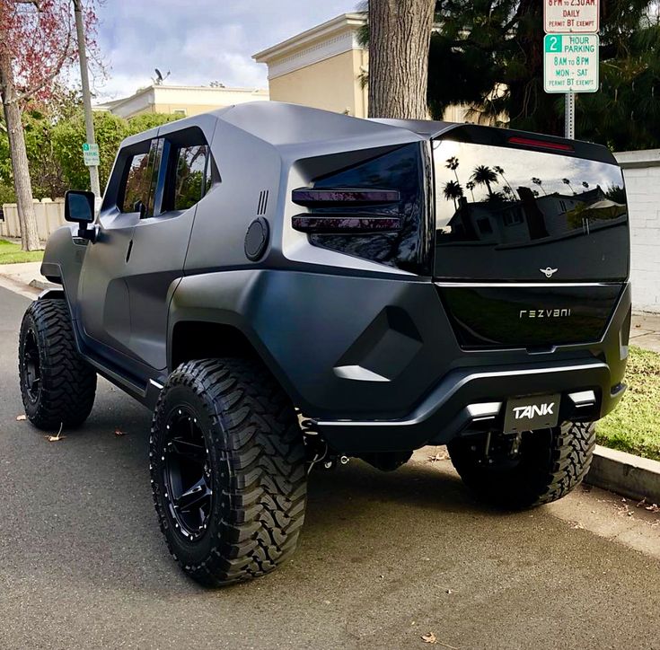 a black hummer truck parked on the side of the road in front of a house