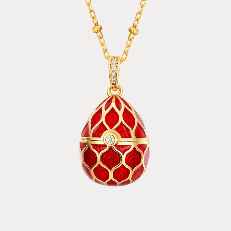 a red and gold necklace with an egg shaped object hanging from it's side