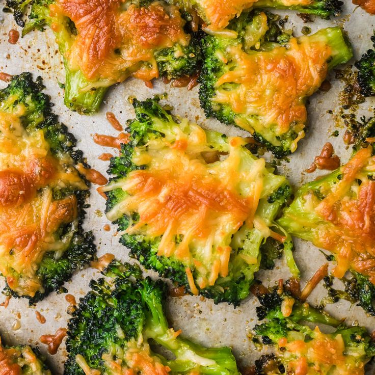 broccoli florets covered in cheese and other toppings on a baking sheet