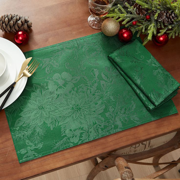 a place setting with green napkins, silverware and pine cones on the table