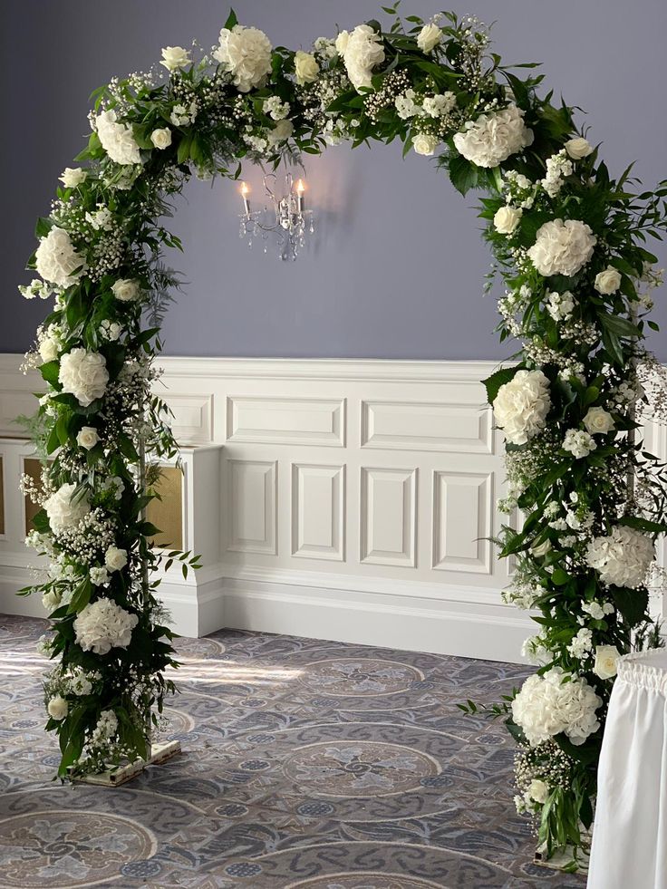 a wedding arch decorated with white flowers and greenery