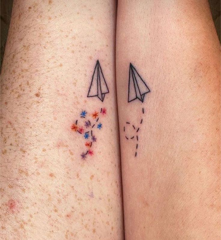 two people with tattoos on their legs, one has a paper airplane and the other has flowers