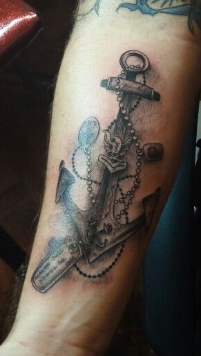 an anchor tattoo on the arm with some keys and chains around it's neck