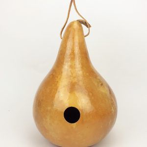 a golden pear shaped vase with a black hole in the middle and a string hanging from it's side