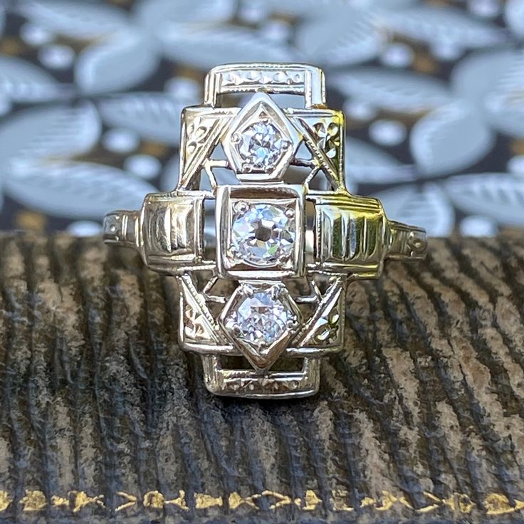 Details: Sweet Art Deco diamond ring set in 14K white gold. This ring has three diamonds, two 2.95mm round, and one 3.3mm round. Interior band stamped 14K. This is a sweet ring--you will not be disappointed! Please ask all necessary questions prior to placing an order. Measurements: The size is 6 US and can be sized for a fee. The face of the ring measures 18mm x 9mm. Condition: The overall all condition of this ring is very good. Antique Platinum Three Stone Diamond Ring, Antique Three-stone Diamond White Rings, Antique Three Stone Diamond White Rings, Antique Three Stone Diamond Ring In Diamond White, 14k Gold Three-stone Diamond Ring For Anniversary, Anniversary 14k Gold Three-stone Diamond Ring, 14k Gold Three Stone Diamond Ring For Anniversary, Art Deco Diamond Three Stone Ring, Vintage 14k Gold Three-stone Rings