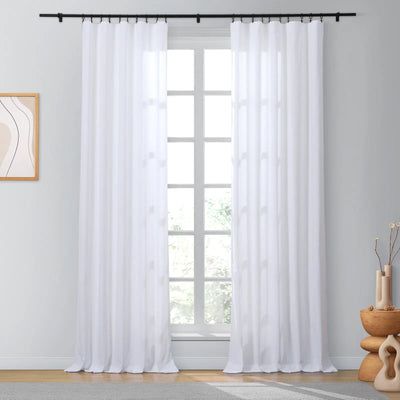 a white curtain hanging in front of a window next to a vase and potted plant