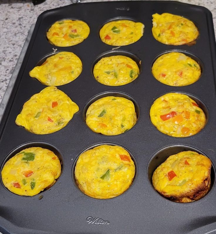 muffin tins filled with eggs on top of a granite countertop next to an oven