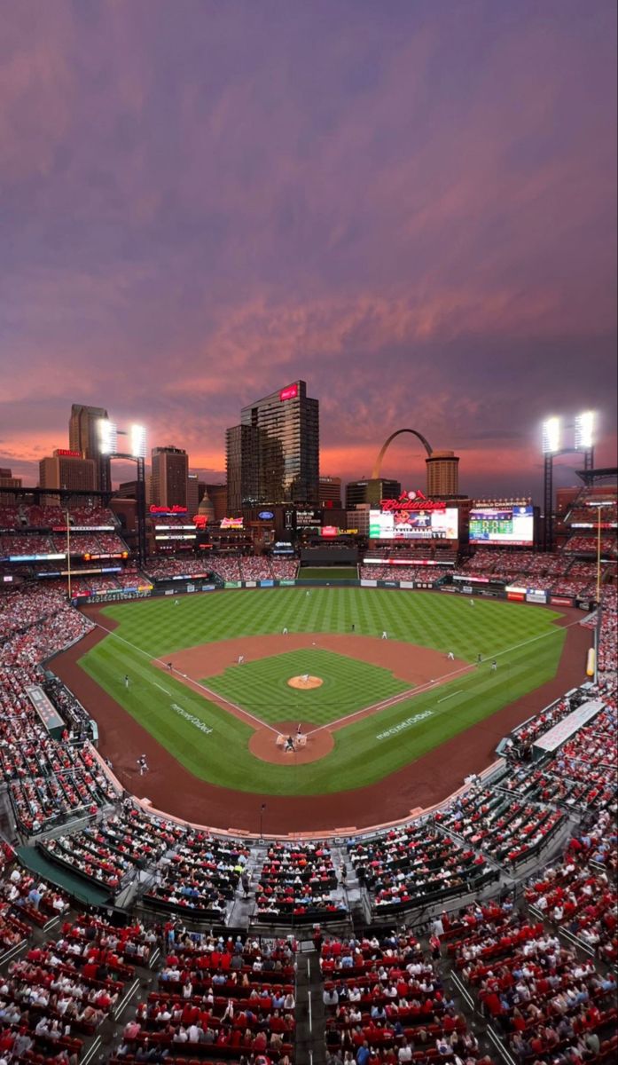 a baseball stadium filled with lots of people sitting in the bleachers at sunset