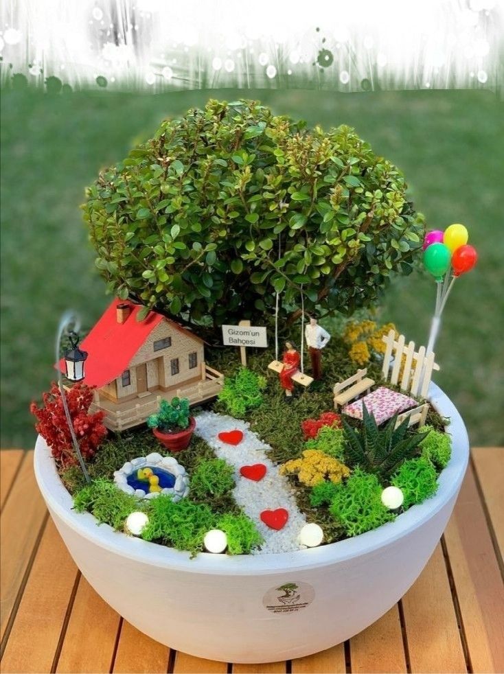 a potted plant with a small house in the center and balloons floating around it