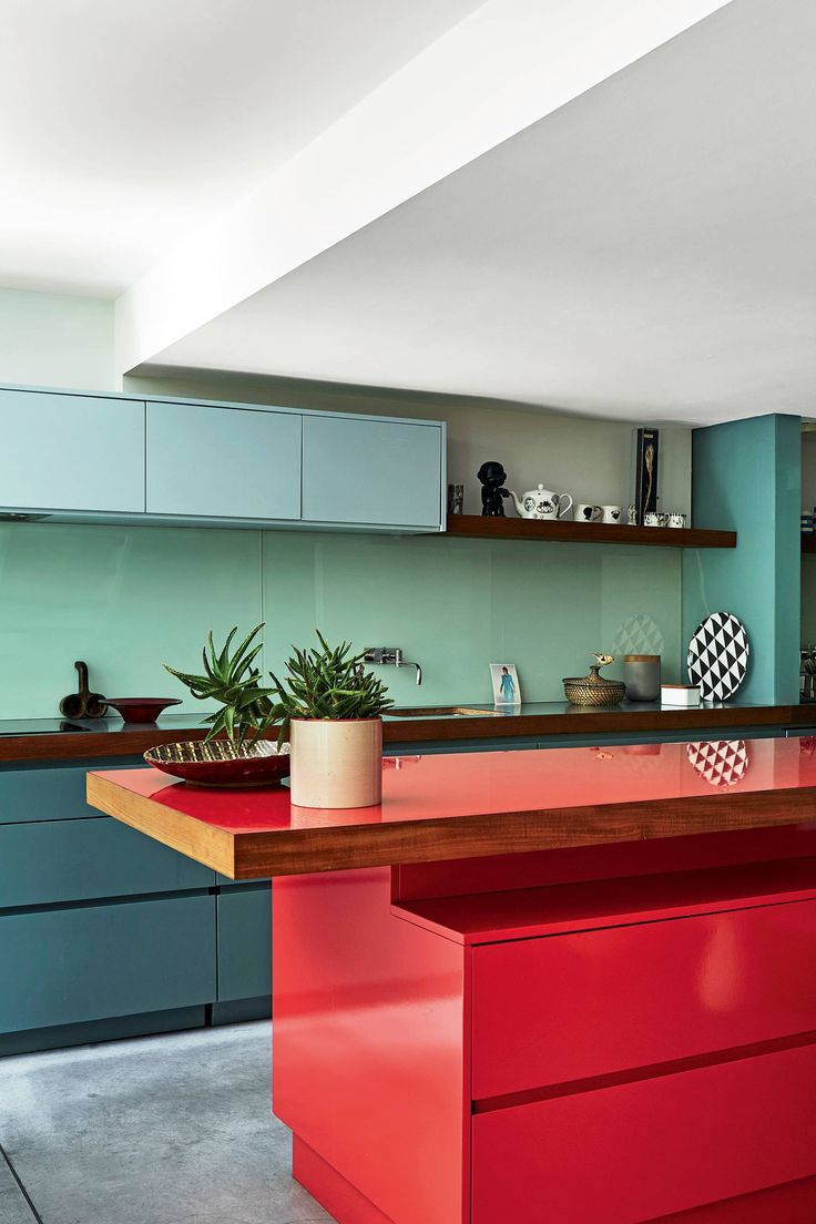 a kitchen with red counter tops and blue cabinets in the backround, along with potted plants