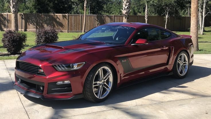 a red mustang parked in front of a house