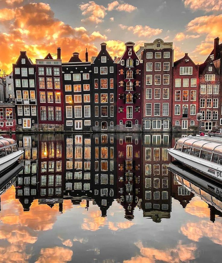 several boats are parked in front of some buildings on the water at sunset or sunrise