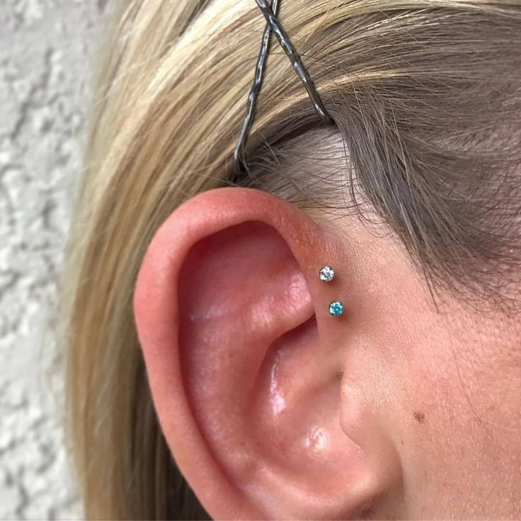 a woman's ear has three small blue stones on it and is attached to a wire