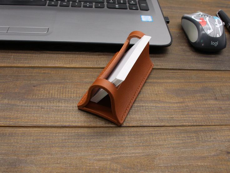 a leather case sitting on top of a wooden table next to a laptop computer and mouse