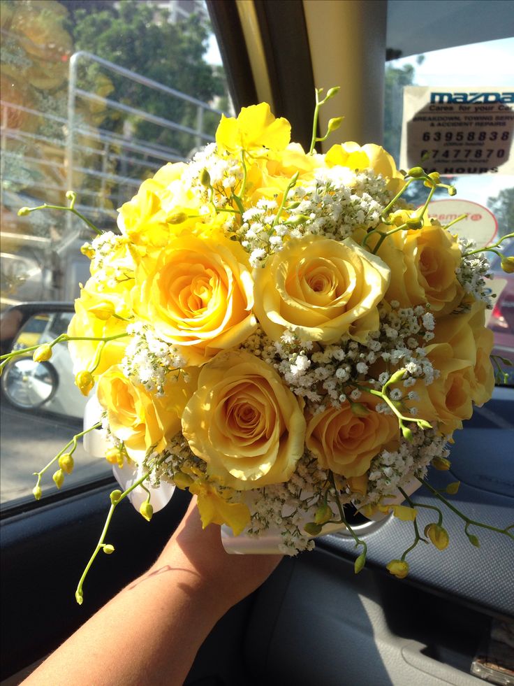 a bouquet of yellow roses and baby's breath in the passenger seat of a car