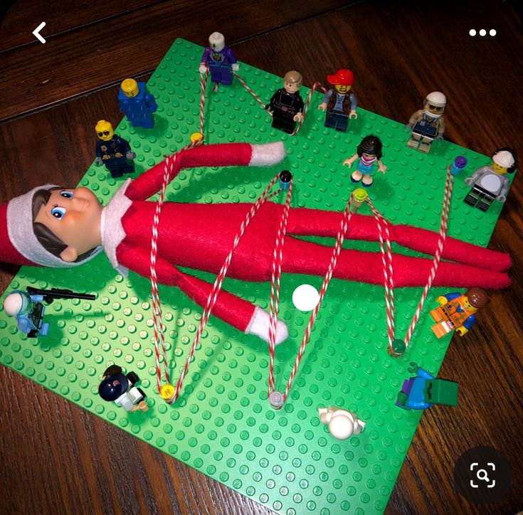 an elf laying on top of a green mat next to legos and other toys