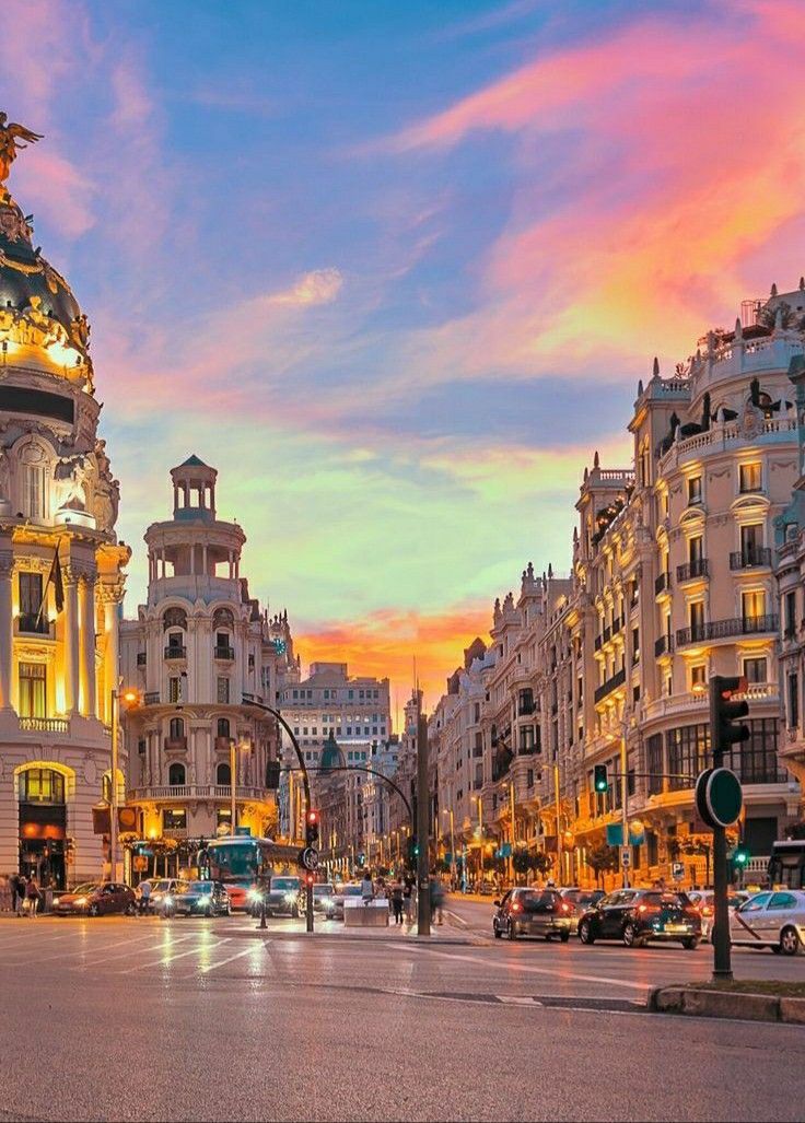 a city street filled with lots of traffic and tall buildings at sunset or dawn in the background