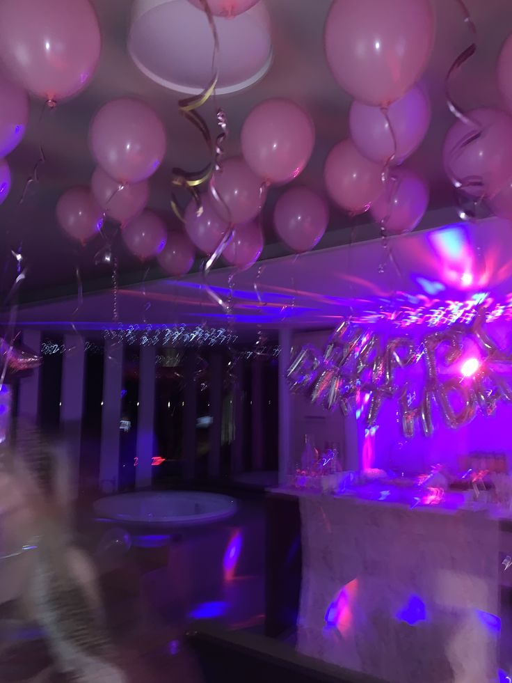 balloons and streamers are floating in the air above a room with purple lighting,