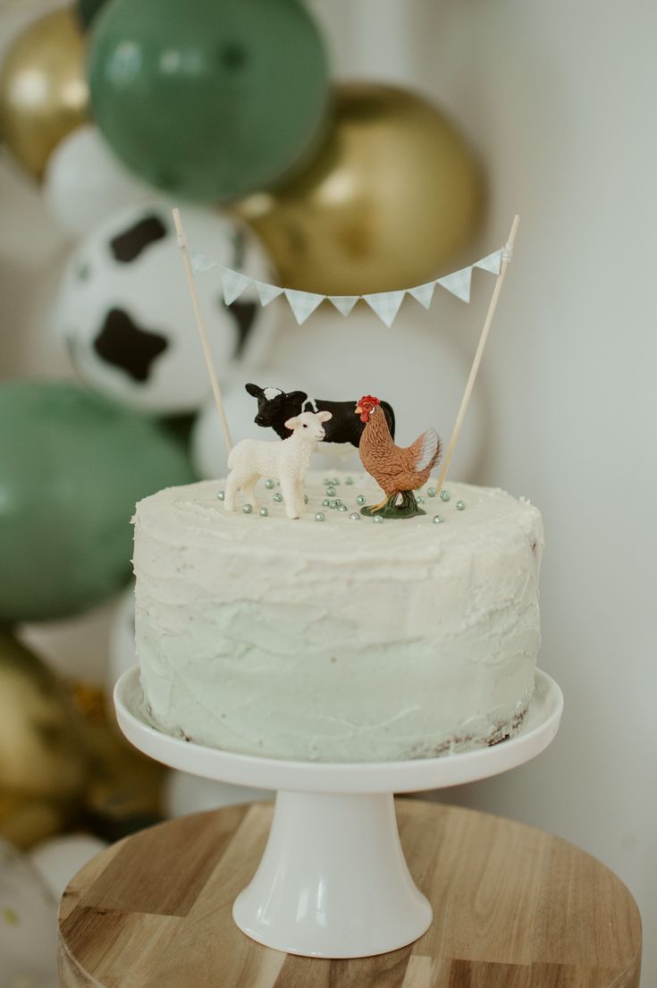 there is a cake with animals on it and balloons in the backgroung