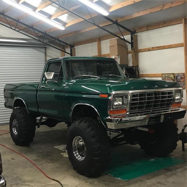 a large green truck parked inside of a garage