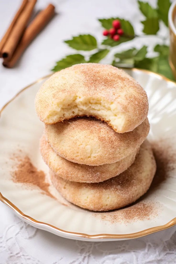 three cinnamon sugar cookies on a plate next to a cup of tea and cinnamon sticks